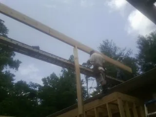 Carpenter setting a ridge beam over a new addition frame — Ice Dam Removal by Roofing Brothers in Seanor