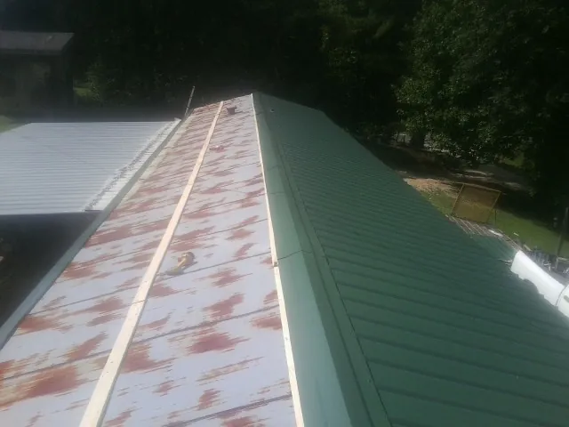 Old rusted panels beside newly installed green metal roofing — Wind Damage Roof Repair by Roofing Brothers in Seanor