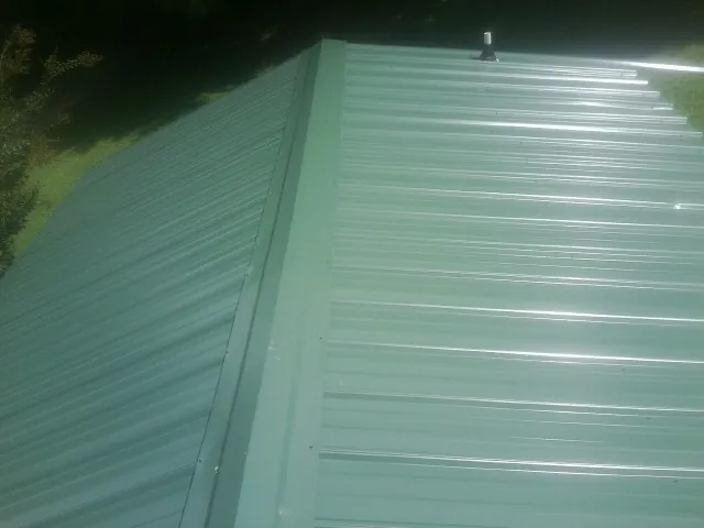 New green metal panels meeting at the ridge of a roof — Flat Roof Repair work by our crew in Seanor