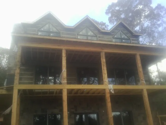Dormers and porch framing on a large log home under construction — Roof Coating work by our crew in Seanor