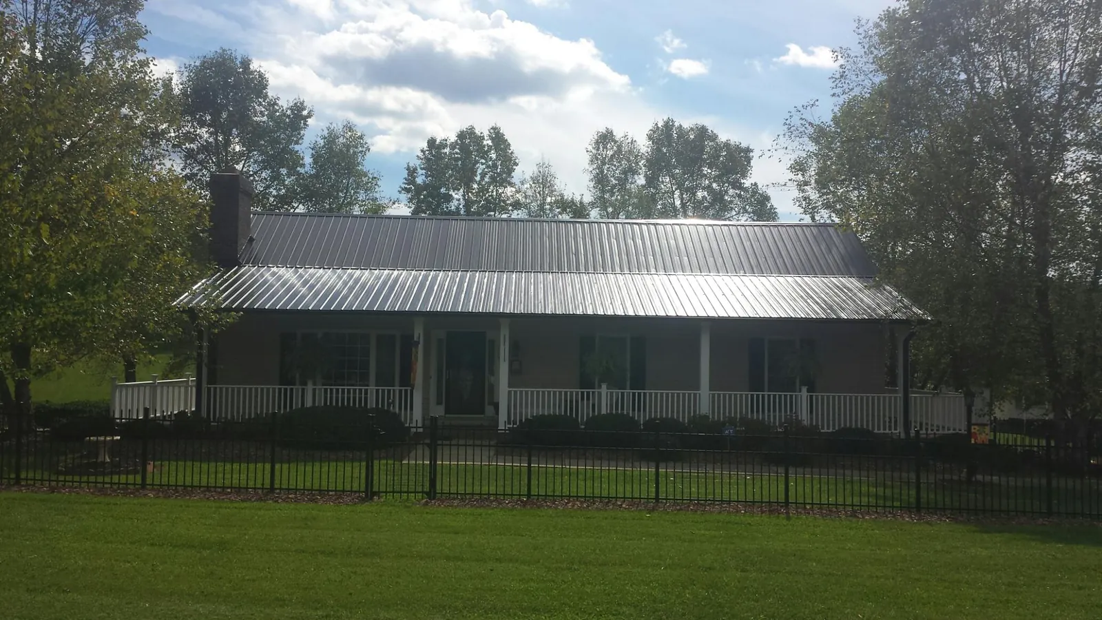 Gray metal roof on a brick ranch with a full width front porch — Gutter Guard Installation work by our crew in Seanor