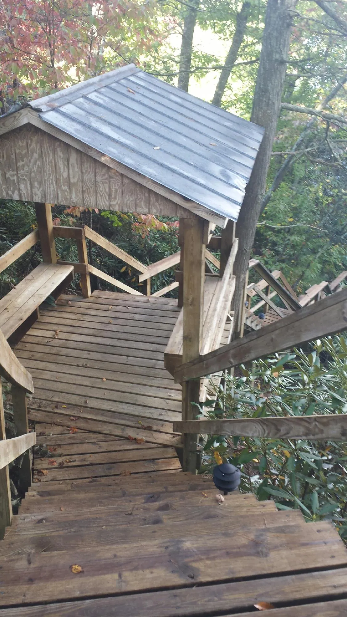 Metal roofed shelter over wooden steps on a wooded walkway — Skylight Repair & Installation work by our crew in Seanor