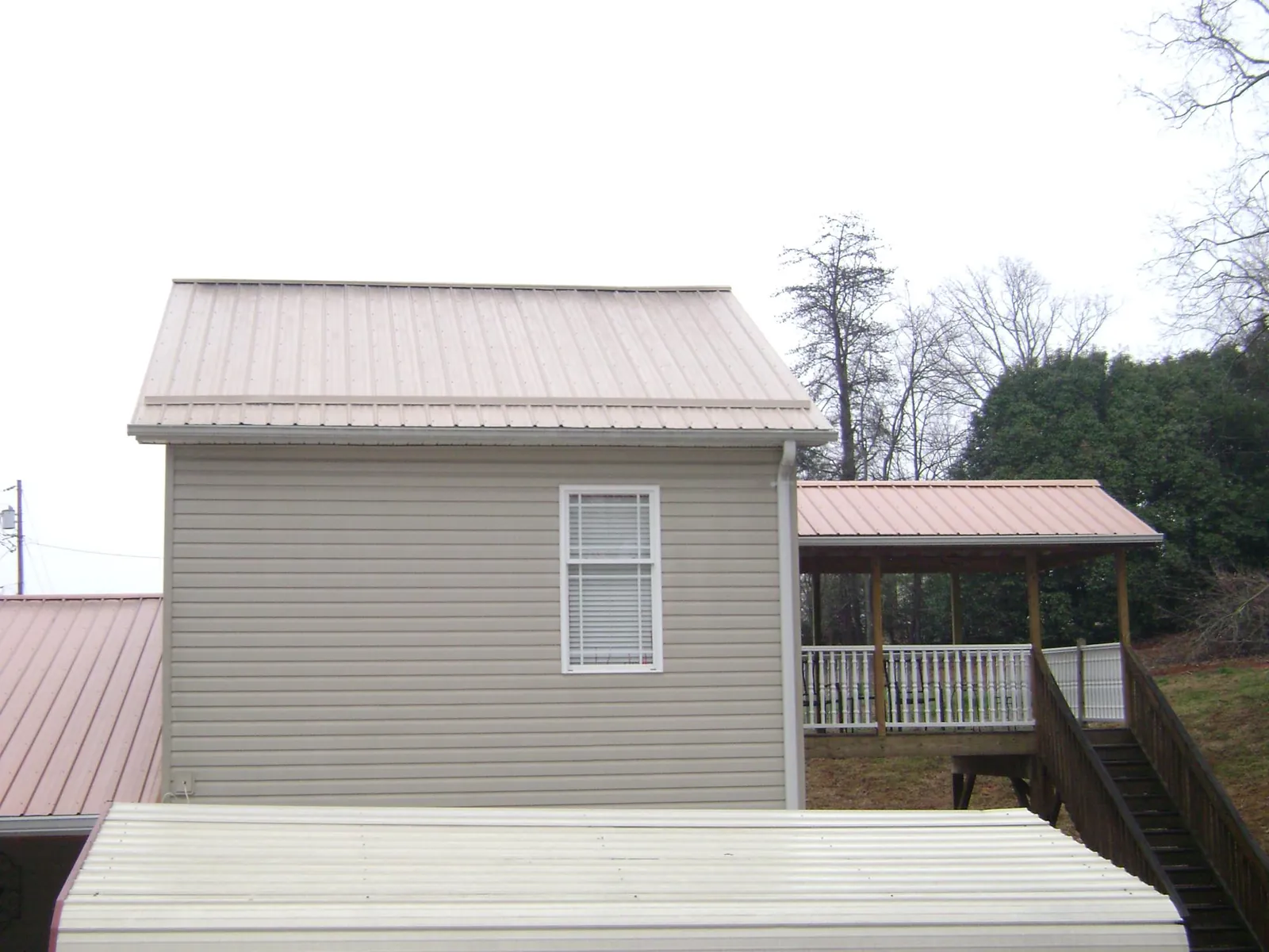Tan metal roofs on a two story addition and attached porch, from a Roof Replacement job in Seanor