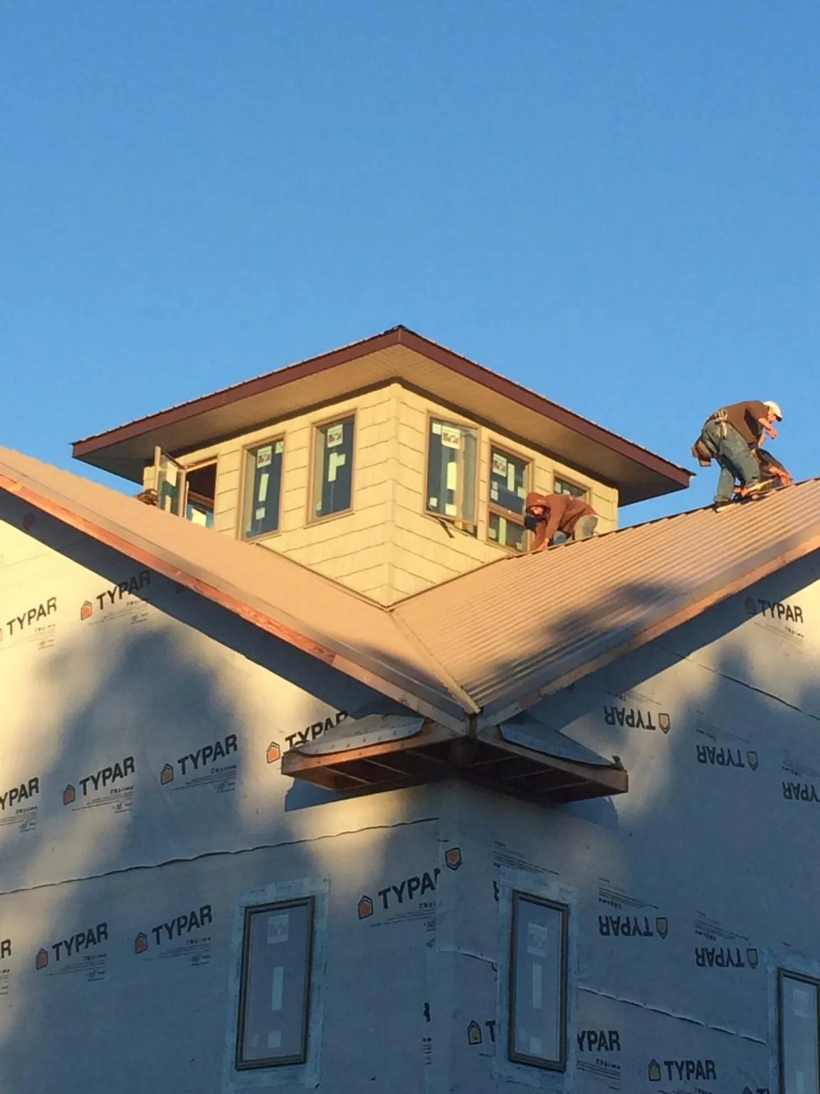 Roofers working around a rooftop cupola on a new metal roof at sunset — Roof Waterproofing in Seanor by Roofing Brothers
